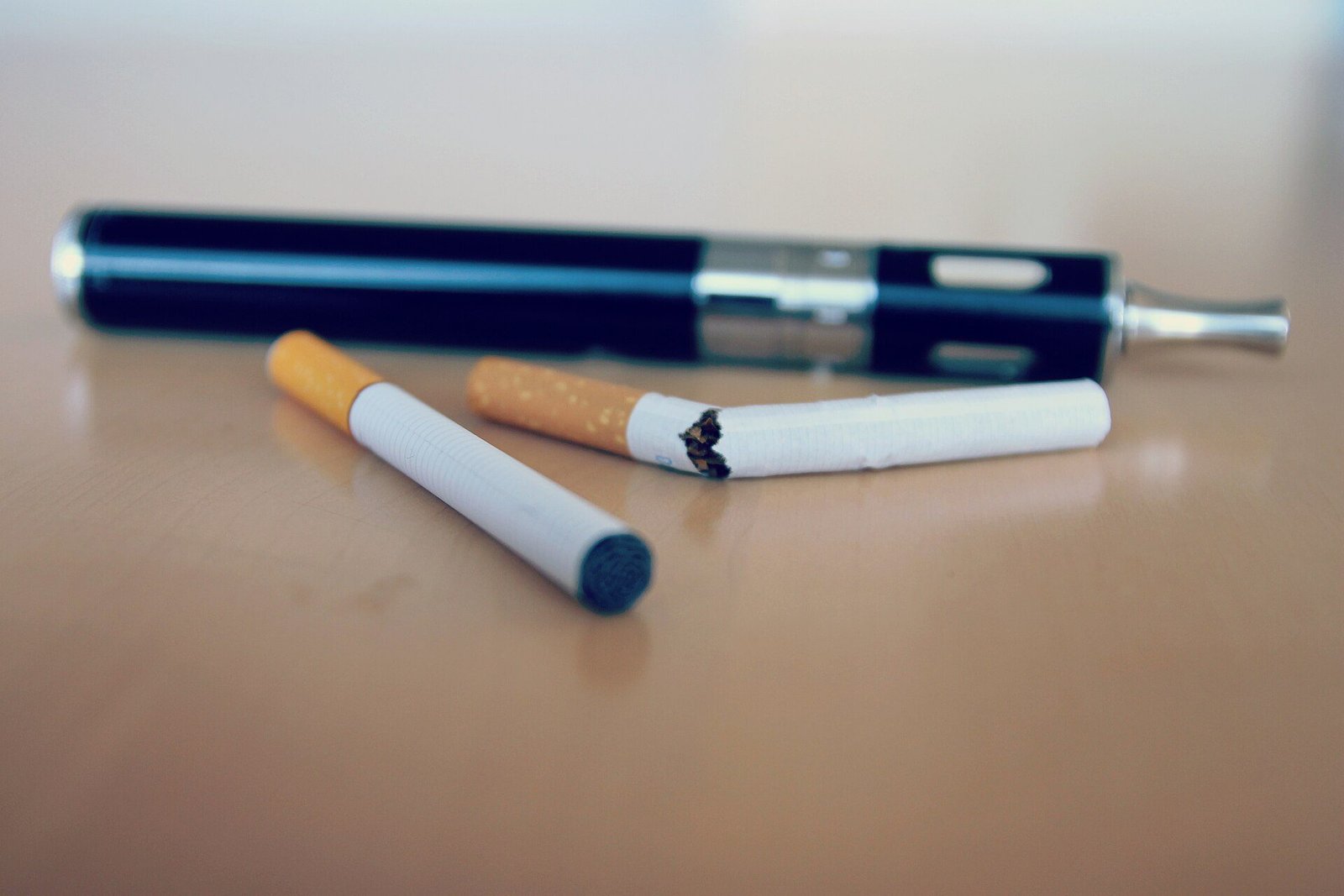 Cigarette cassée en deux posée à côté d'une cigarette intacte et d'une cigarette électronique