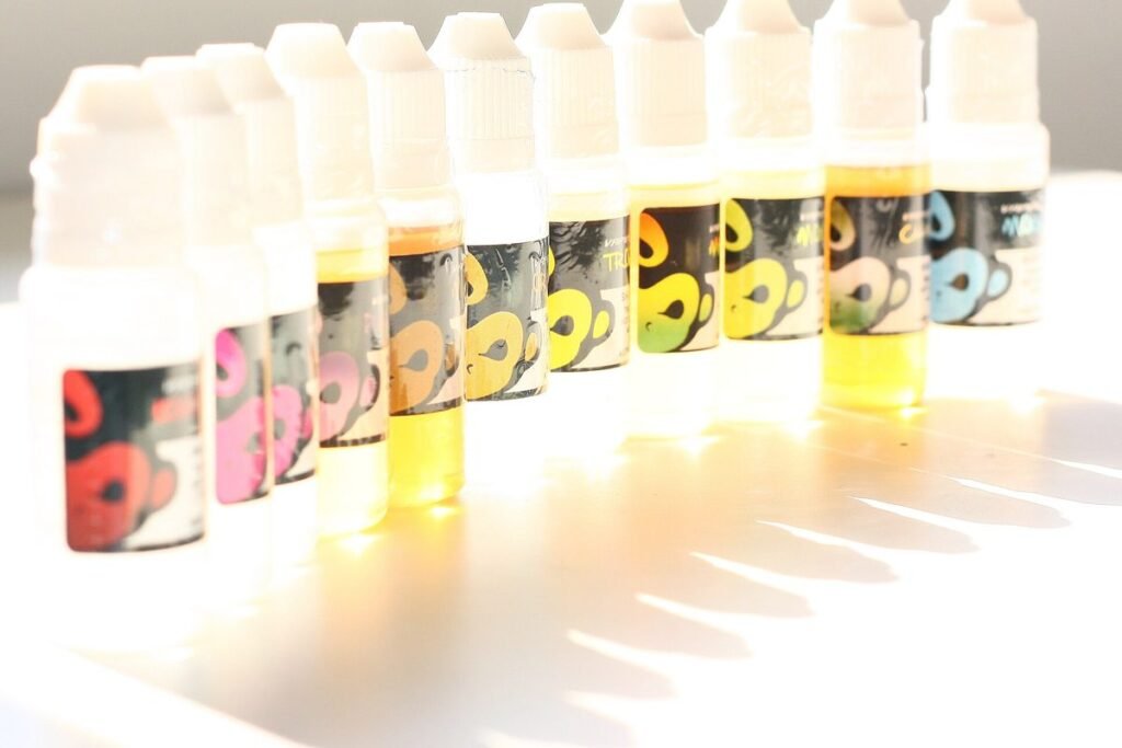 Rangée de petits flacons d'e-liquide aux couleurs variées, éclairés par derrière