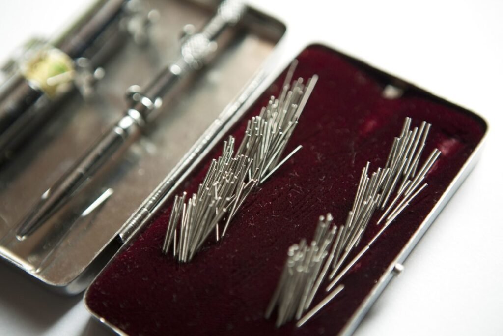Boîte métallique ouverte contenant des aiguilles d'acupuncture fines rangées sur du velours