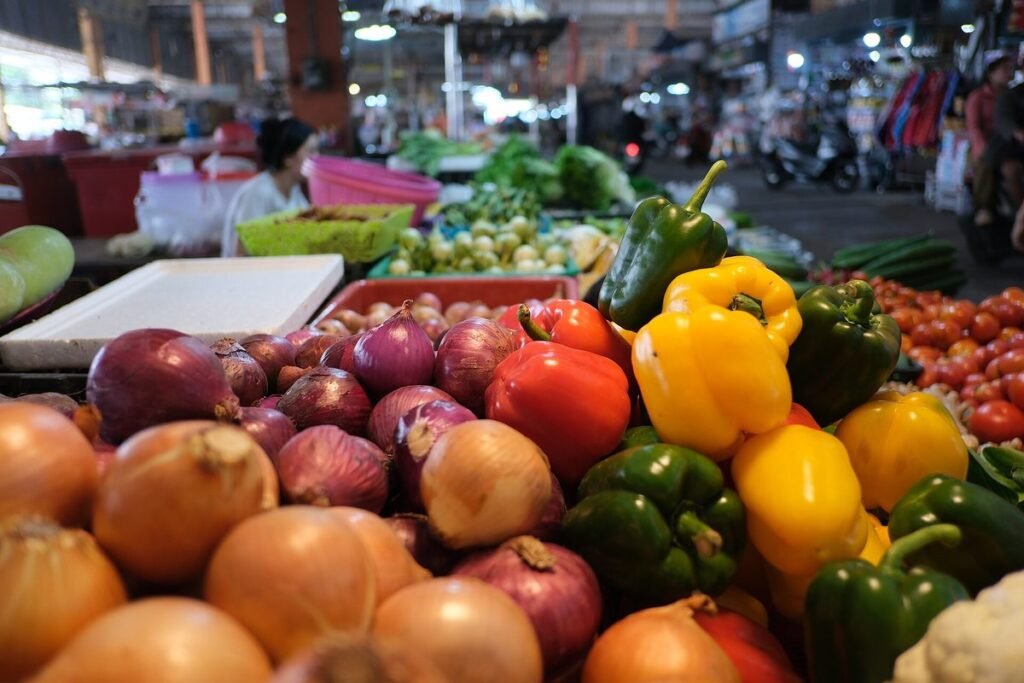 Étal de marché garni d'oignons, de poivrons jaunes et verts et de tomates
