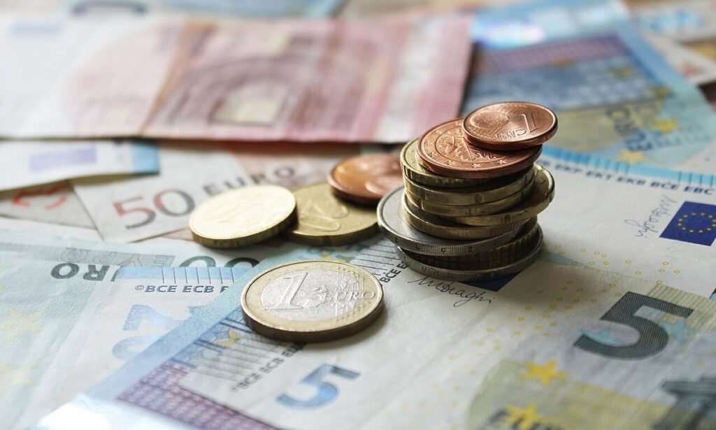 Pile de pièces en euros posée sur des billets de 5, 20 et 50 euros étalés