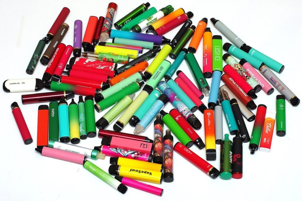 Tas de cigarettes électroniques jetables de toutes les couleurs sur fond blanc