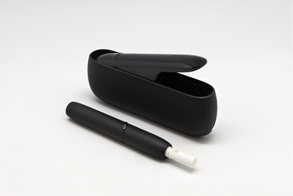 Appareil noir de tabac chauffé avec son étui chargeur ouvert et un stick de tabac inséré